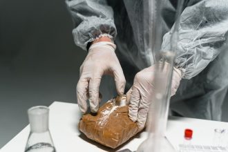 Profissional usando equipamento de proteção analisa uma substância em pó em um laboratório