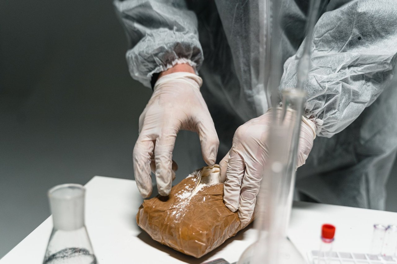 Profissional usando equipamento de proteção analisa uma substância em pó em um laboratório