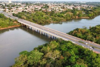 Vista aérea de uma ponte sobre um rio cercado por vegetação, em Cuiabá, Mato Grosso.