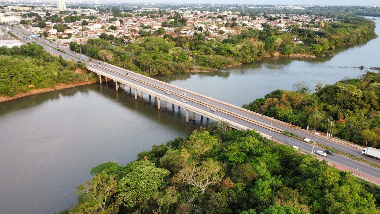 Vista aérea de uma ponte sobre um rio cercado por vegetação, em Cuiabá, Mato Grosso.