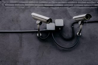 Câmera de vigilância instalada em uma parede, usada para monitoramento e segurança.