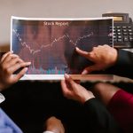 Profissionais analisam um gráfico de dados econômicos durante uma reunião.